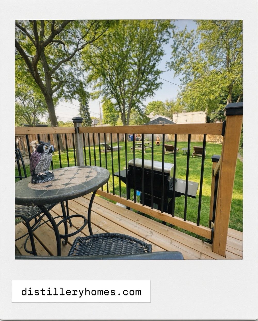 Cedar back deck with black metal balusters, bistro table and barbecue overlooking a large treed backyard at 763 Monmouth Road